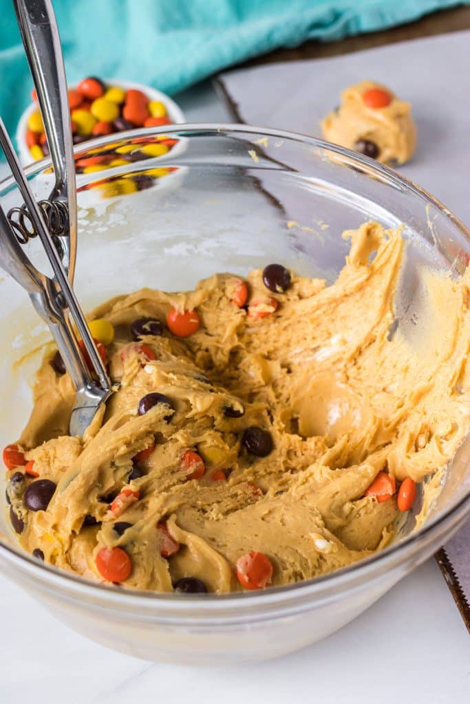 bowl of cookie dough with a cookie scoop stuck in it.