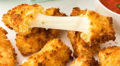 pile of mozzarella cheese sticks with the cheese being pulled apart from a broken one.