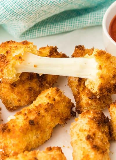 pile of mozzarella cheese sticks with the cheese being pulled apart from a broken one.