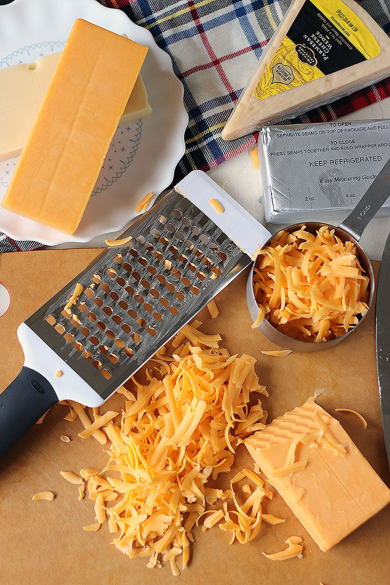 grater and cheese on cutting board for homemade baked mac and cheese 