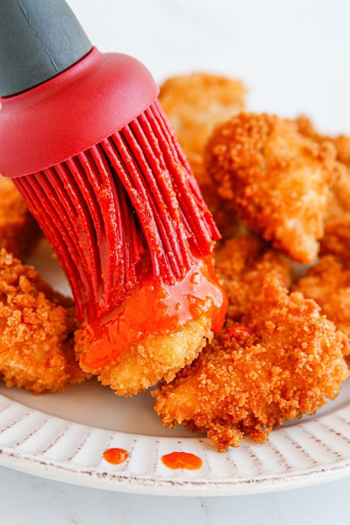 silicone basting brush brushing sauce onto boneless chicken wings.