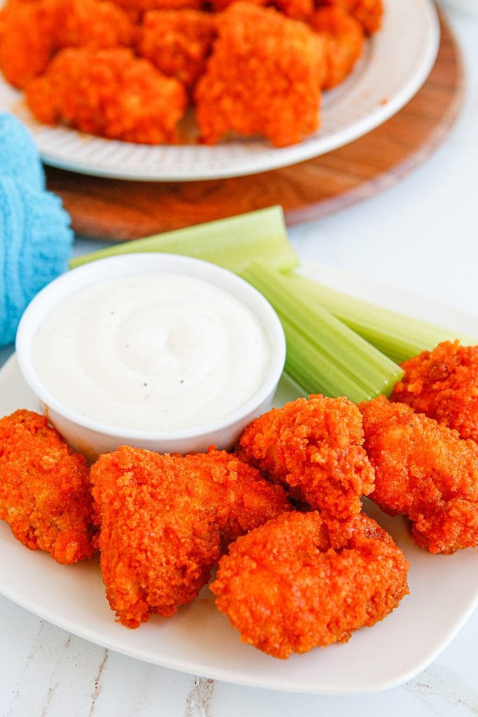 a plate of boneless chicken wings with a cup of ranch dressing for dipping.