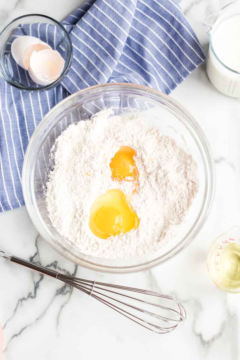 mixing bowl with flour, eggs, whisk