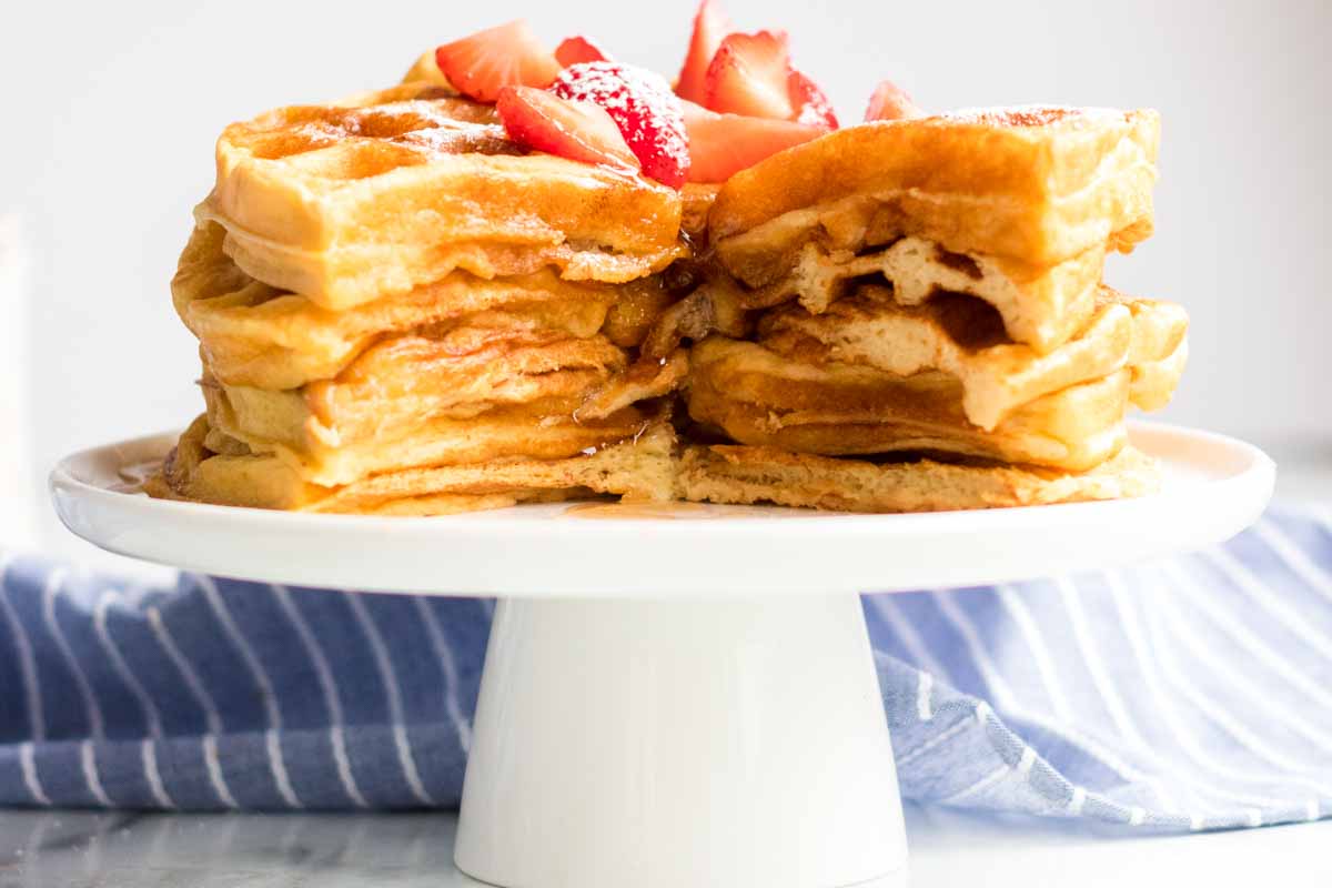 stack of 6 buttermilk waffles cut into with syrup and strawberries