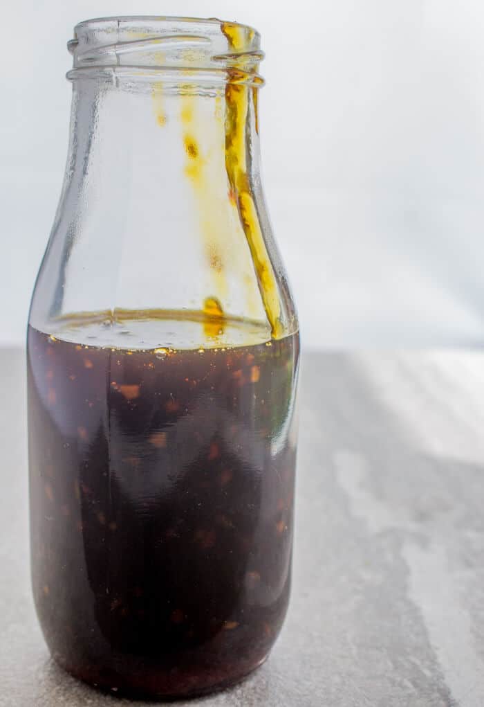 glass bottle full of sauce dripping over edge