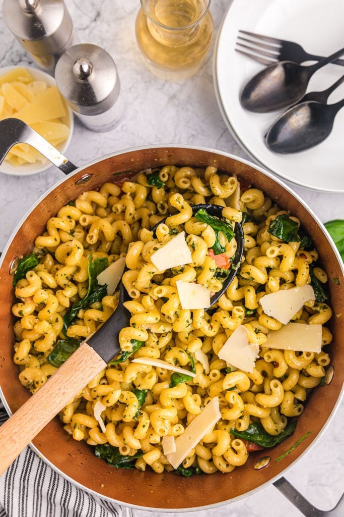 spoon lifting a scoop of pesto cavatappi from a pot.