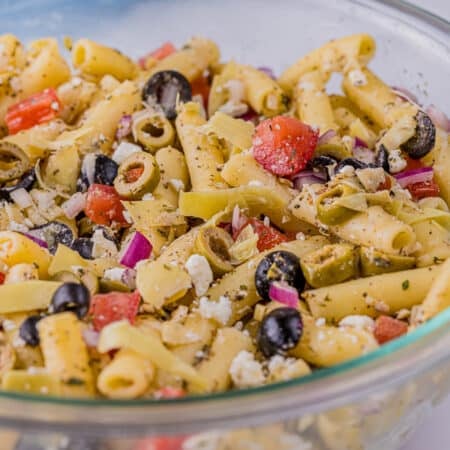 greek pasta salad with artichokes and olives in a glass bowl.