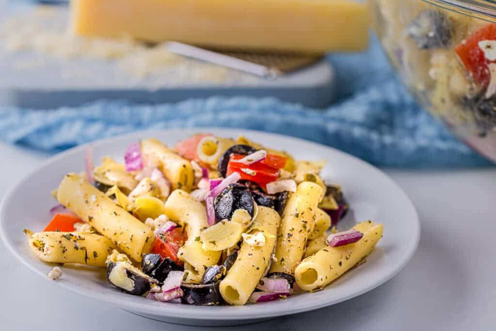 portion of greek pasta salad on a white plate.