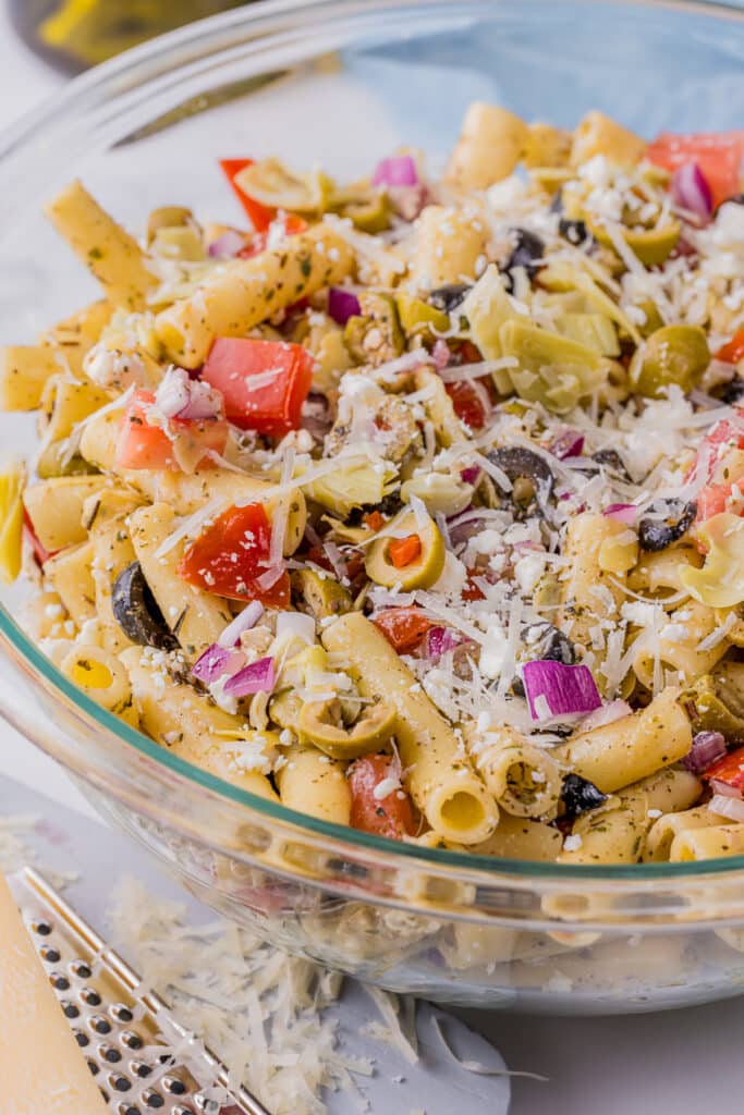 greek pasta salad topped with parmesan cheese in a serving bowl.