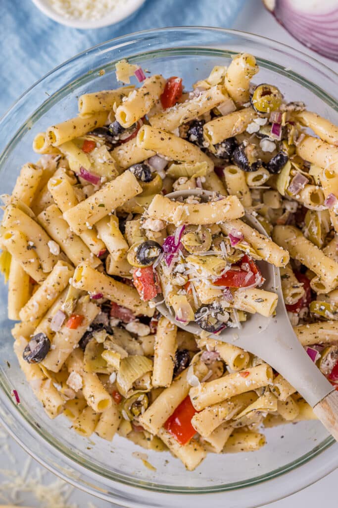 spoon lifting a scoop of greek pasta salad from a bowl.