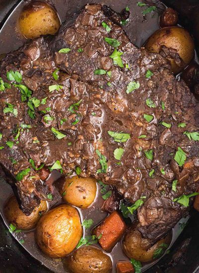 overhead shot of roast beef, potatoes, and carrots in a crock pot.
