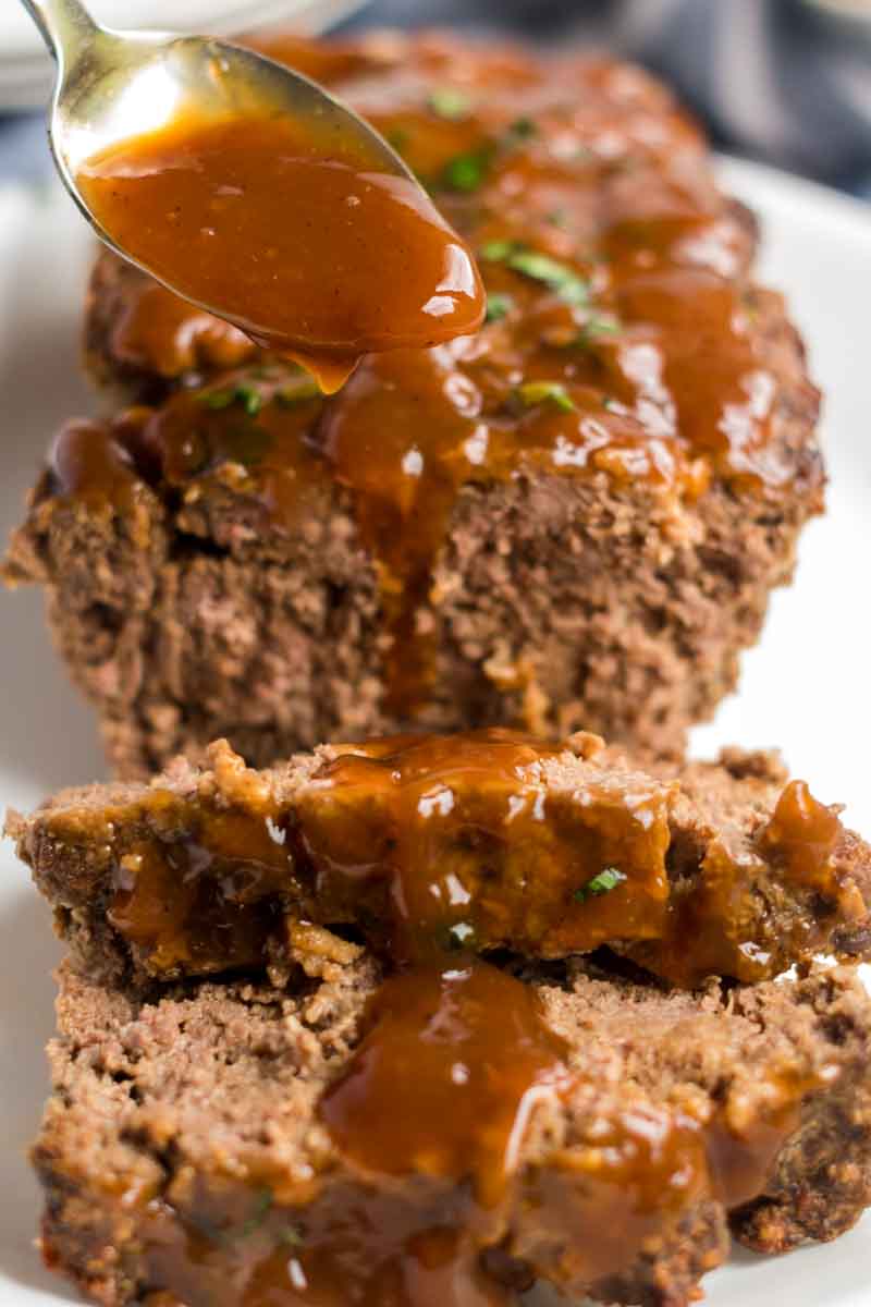 sliced meatloaf with brown gravy pouring over top