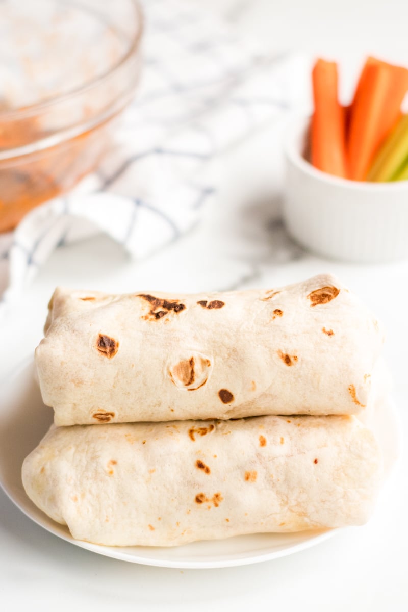 wrapped buffalo ranch chicken wraps stacked with carrots in background 