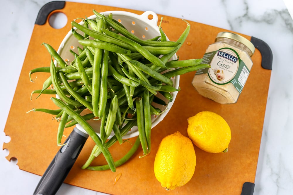 fresh green beans in colander with lemons and garlic