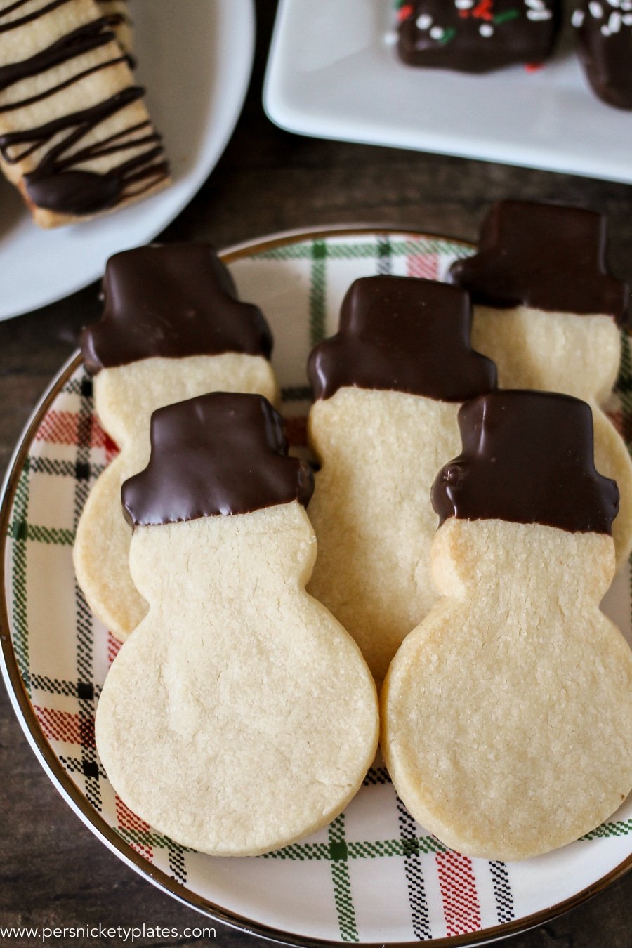 plate of snowman shaped shortbread cookies with chocolate dipped hats