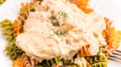 white plate with tri-colored noodles topped with creamy italian chicken.