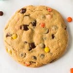 overhead shot of a giant peanut butter cookie with chocolate chips & reese's pieces.