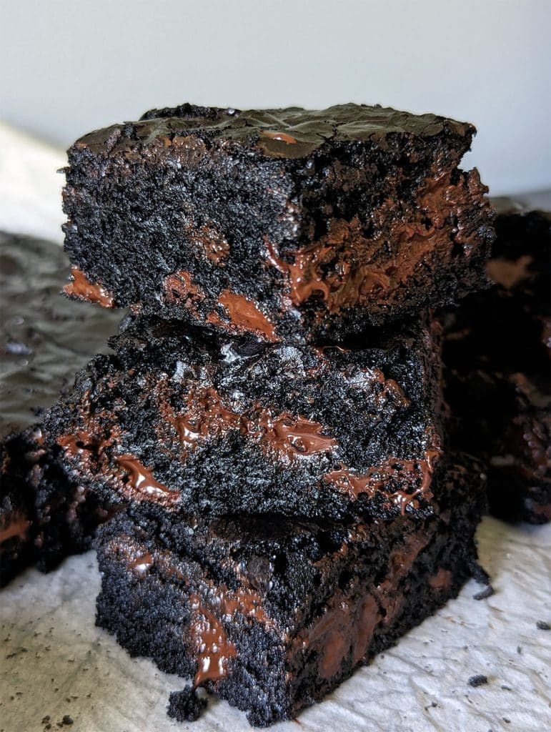 stack of 3 dark chocolate brownies with melty chocolate chips inside.