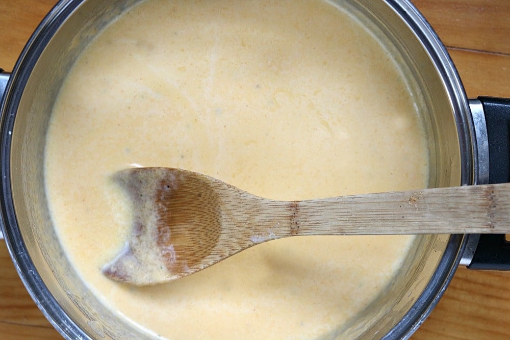 melted cheese sauce with a wooden spoon in a saucepan