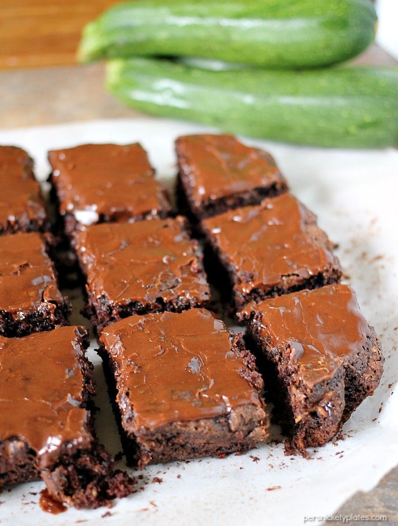 sliced, frosted brownies in front of zucchini.