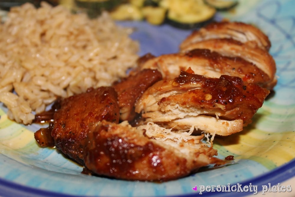 honey bourbon chicken sliced on a plate next to brown rice.