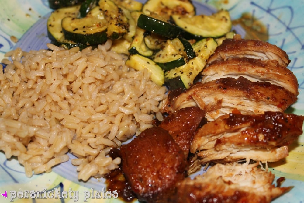 overhead shot of bourbon chicken, brown rice, and zucchini on a dinner plate.