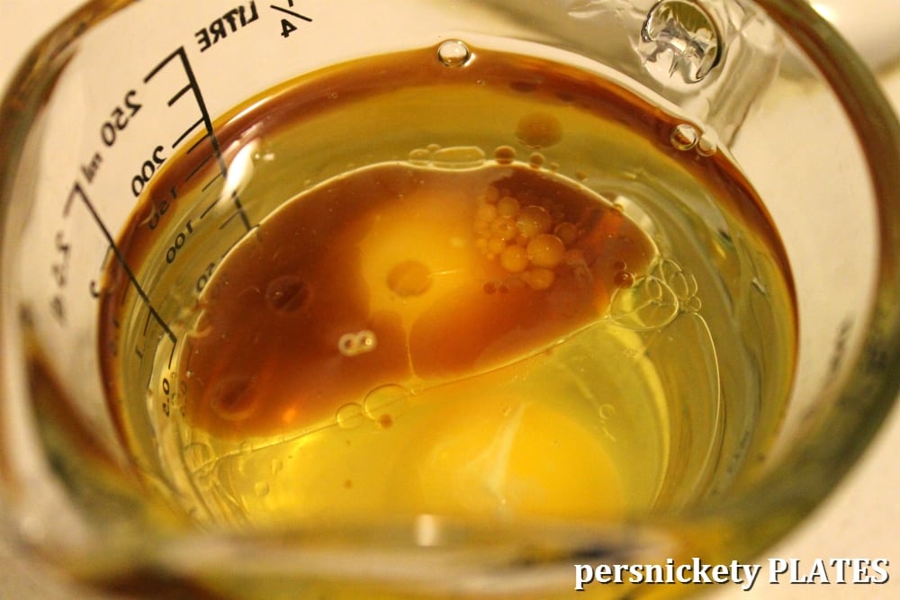 measuring cup with oil, vanilla extract, and egg