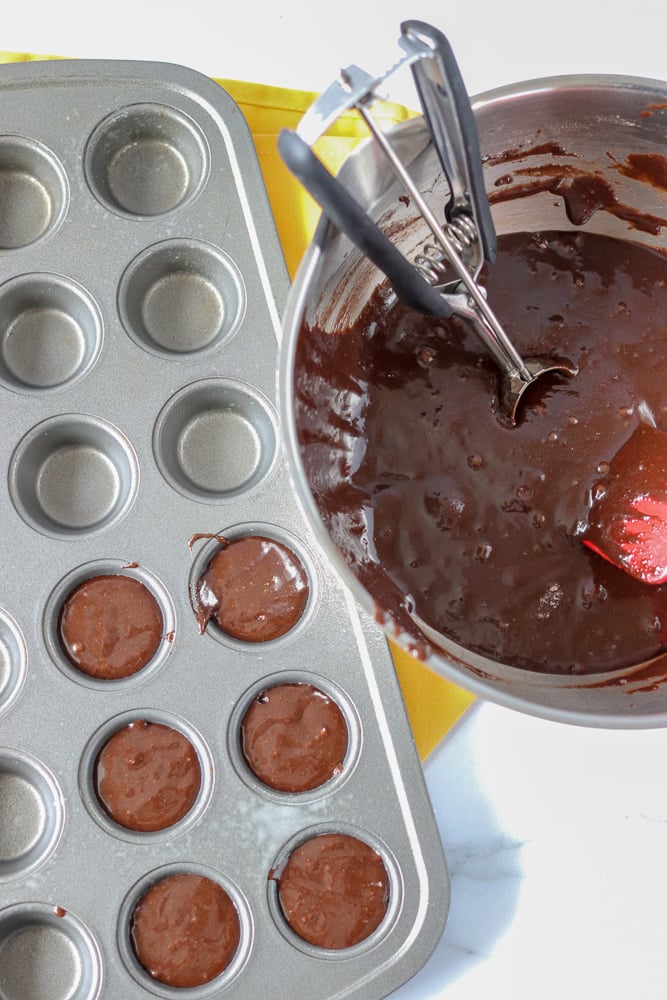 brownie batter being scooped into a mini muffin tray