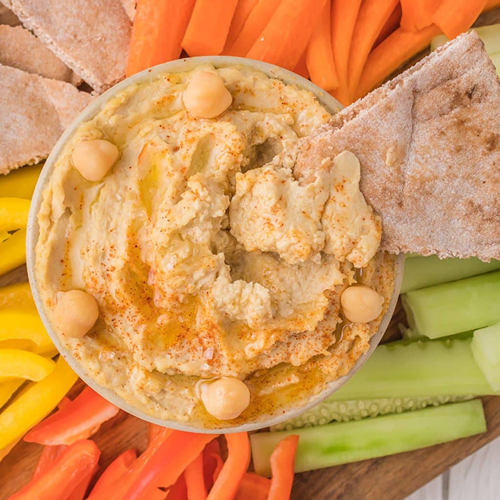 overhead shot of hummus surrounded by veggies.
