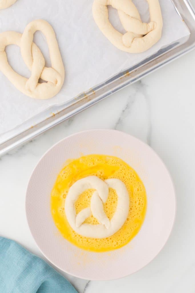 pretzel dough in a bowl of egg wash.
