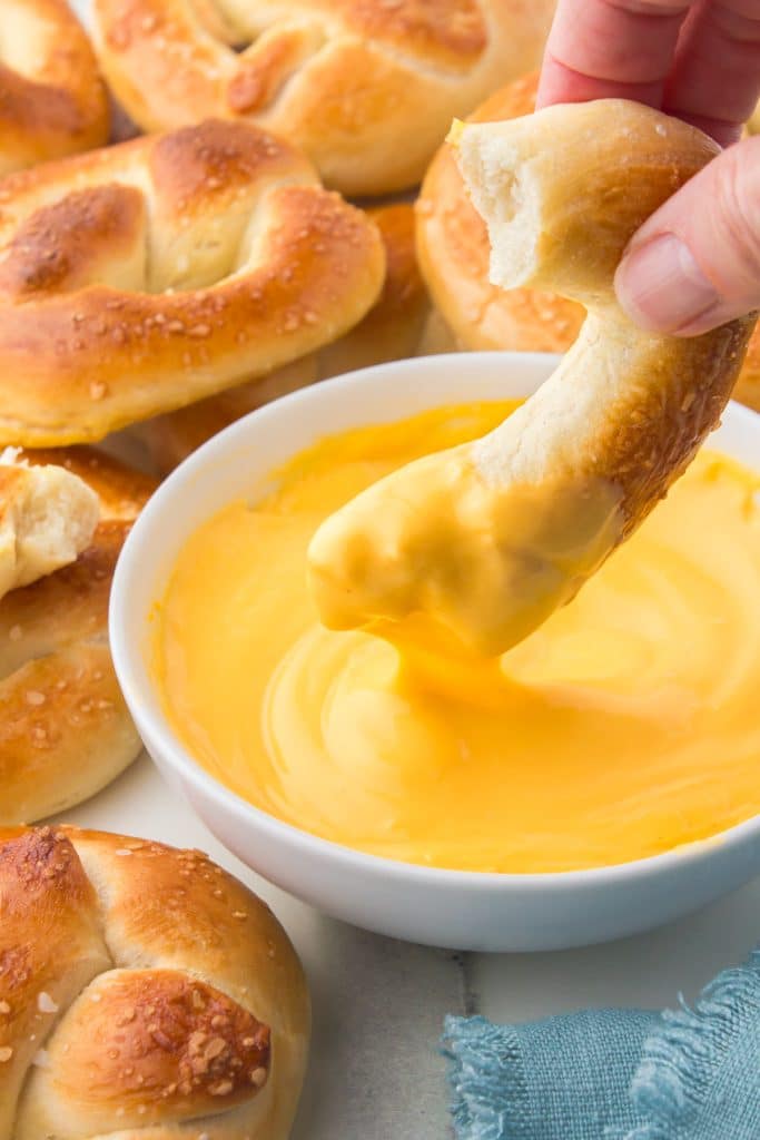 soft pretzel piece dipping into cheese sauce.