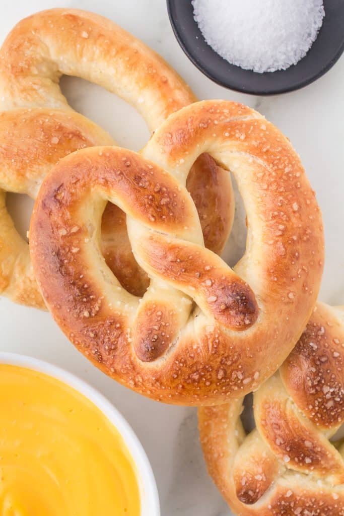 overhead shot of a soft pretzel next to a bowl of cheese and sea salt.