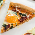 slice of bacon & spinach breakfast pizza with egg yolk