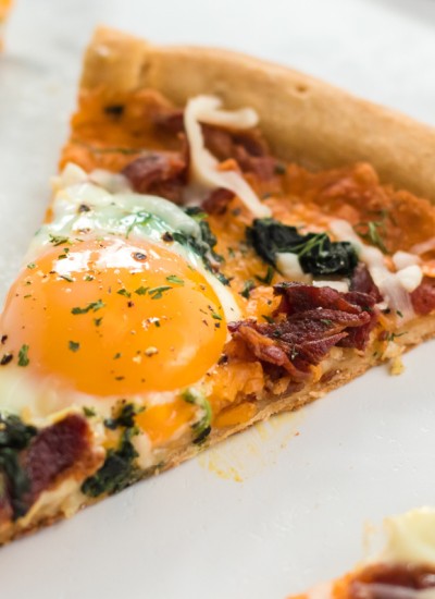 slice of bacon & spinach breakfast pizza with egg yolk