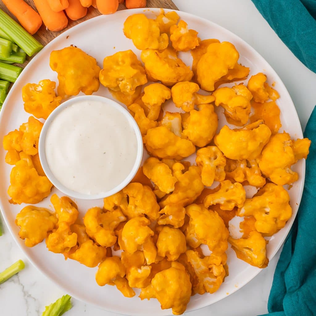 overhead shot of platter of buffalo cauliflower bites with cup of ranch.