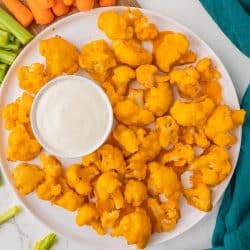overhead shot of platter of buffalo cauliflower bites with cup of ranch.