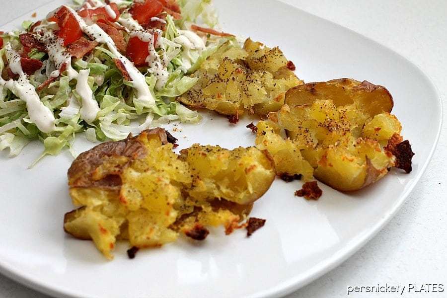 crash hot potatoes on a white plate with a side salad