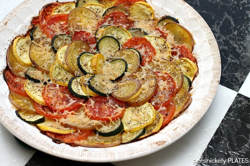 Vegetable Tian is a delicious vegetarian dish made with zucchini, squash, tomatoes, and red skin potatoes, baked together and sprinkled with cheese. This colorful vegetable recipe makes a beautiful side dish or a main vegetarian meal. 