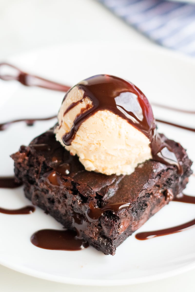 coconut oil brownie topped with vanilla ice cream and chocolate sauce 