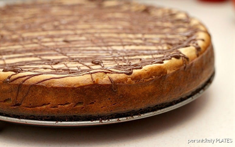 Brownie Bottom Peanut Butter Cheesecake has a layer of chewy brownie topped with a creamy peanut butter cheesecake and drizzled with rich chocolate. | www.persnicketyplates.com #cheesecake #peanutbutter #brownie #dessert