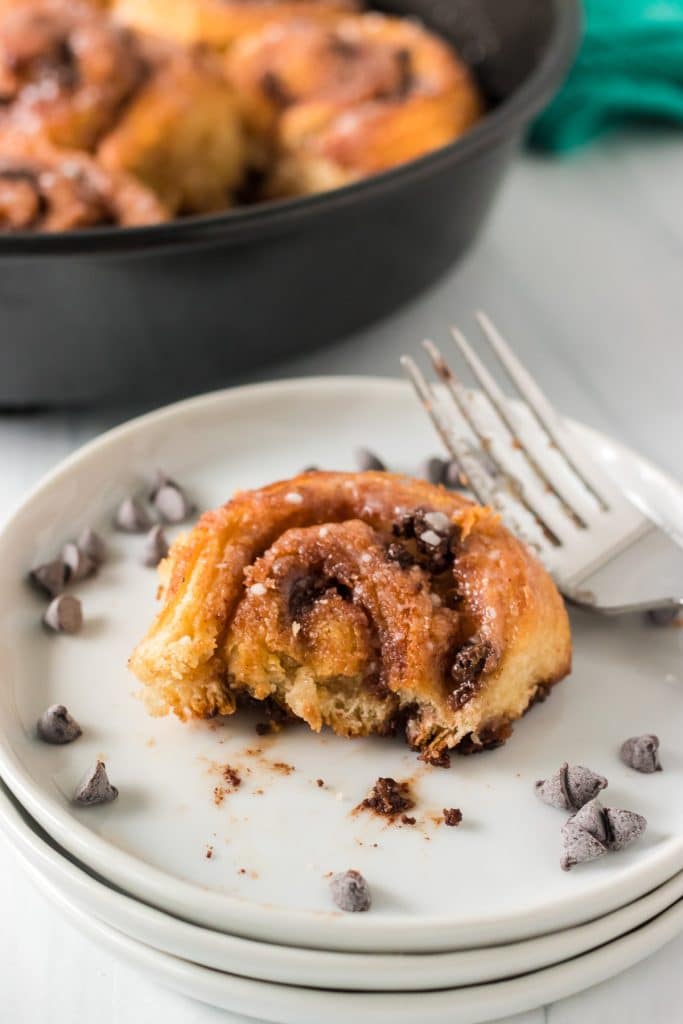 chocolate chip crescent roll cinnamon roll on a white plate with a bite missing.