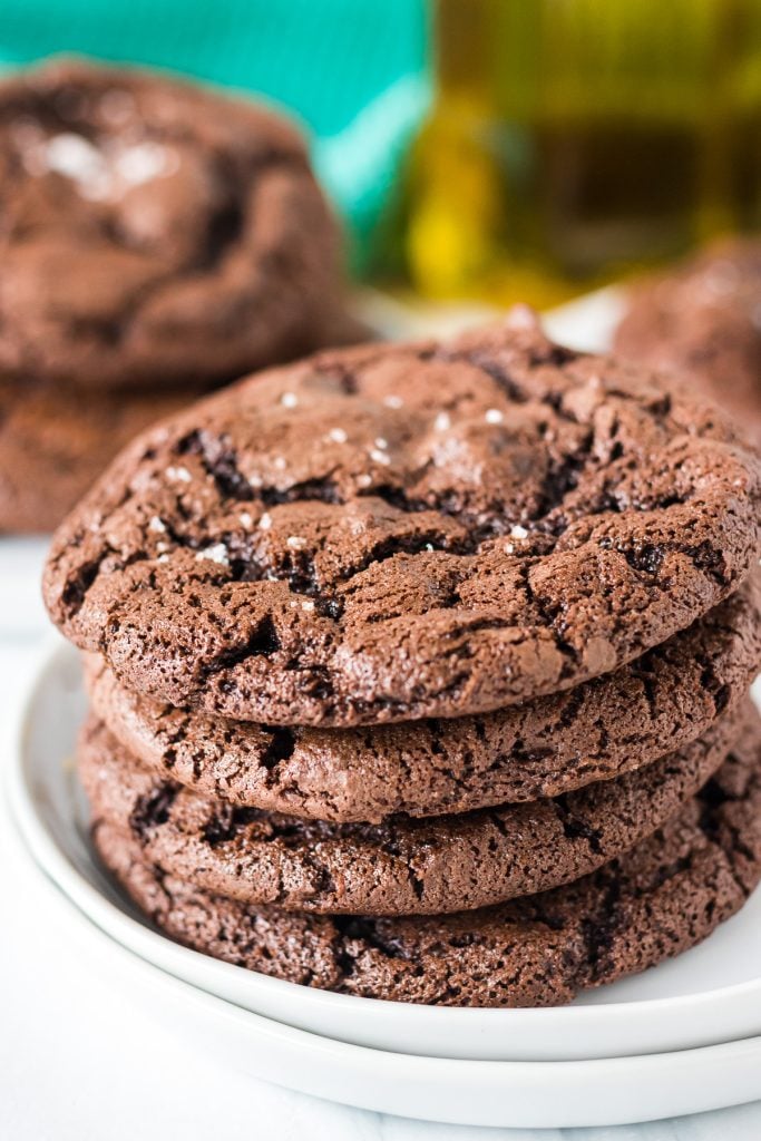 stack of chocolate brownie cookies on a white plate with olive oil in background