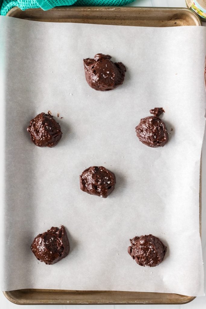 overhead shot of raw brownie batter cookie balls on a baking sheet