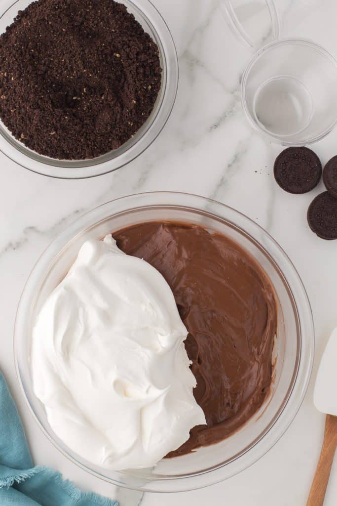 whipped topping being added to a bowl of chocolate pudding.
