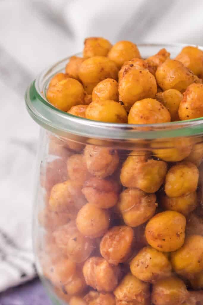 side view of a glass jar filled with roasted chickpeas.
