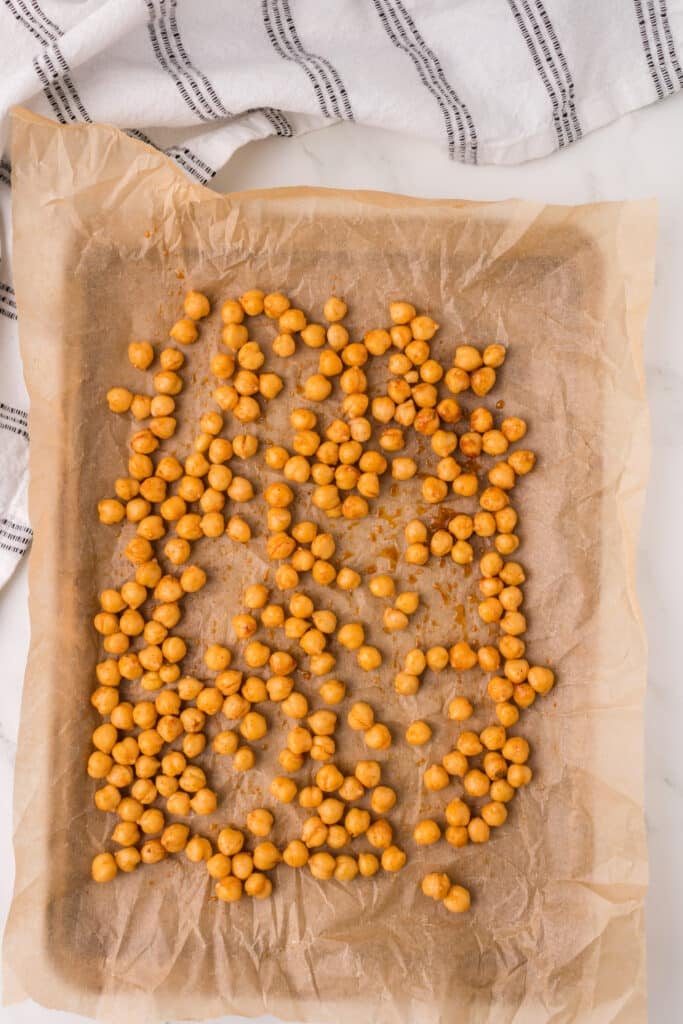 seasoned chickpeas laid out on a parchment lined baking sheet.