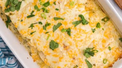 overhead shot of a pan of salsa verde chicken enchiladas topped with cheese & cilantro.