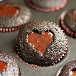 Dark chocolate cupcakes with a heart shaped cut-out filled with chocolate ganache and topped with sprinkles. Perfect for Valentine's Day!