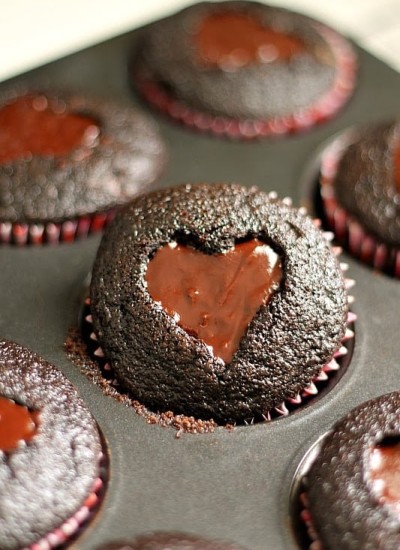 Dark chocolate cupcakes with a heart shaped cut-out filled with chocolate ganache and topped with sprinkles. Perfect for Valentine's Day!