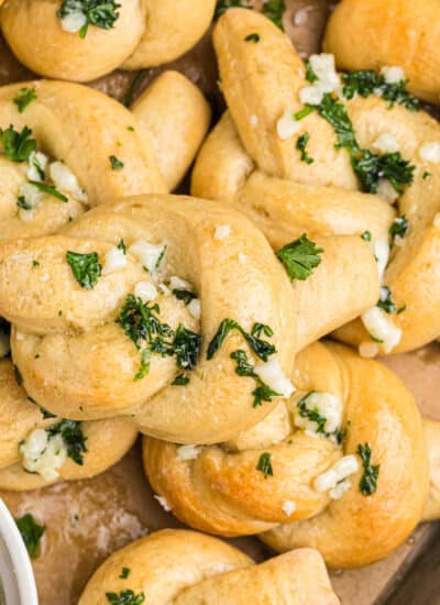 overhead shot of a pile of garlic knots topped with parsley.